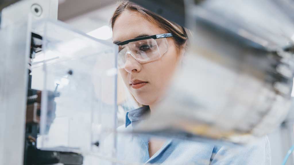 Female industrial worker working with manufacturing equipment in a factory