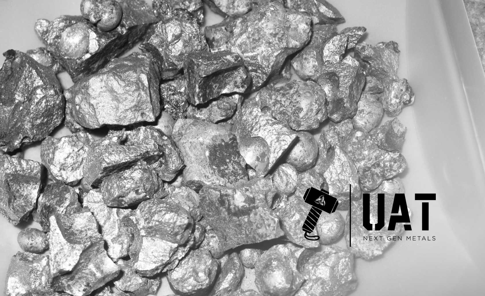 Titanium ore in pan with UAT logo in bottom right of image.